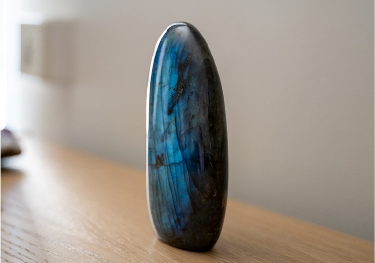 Pierre de labradorite posée sur une table en bois – symbole de protection et de sensibilité intuitive.