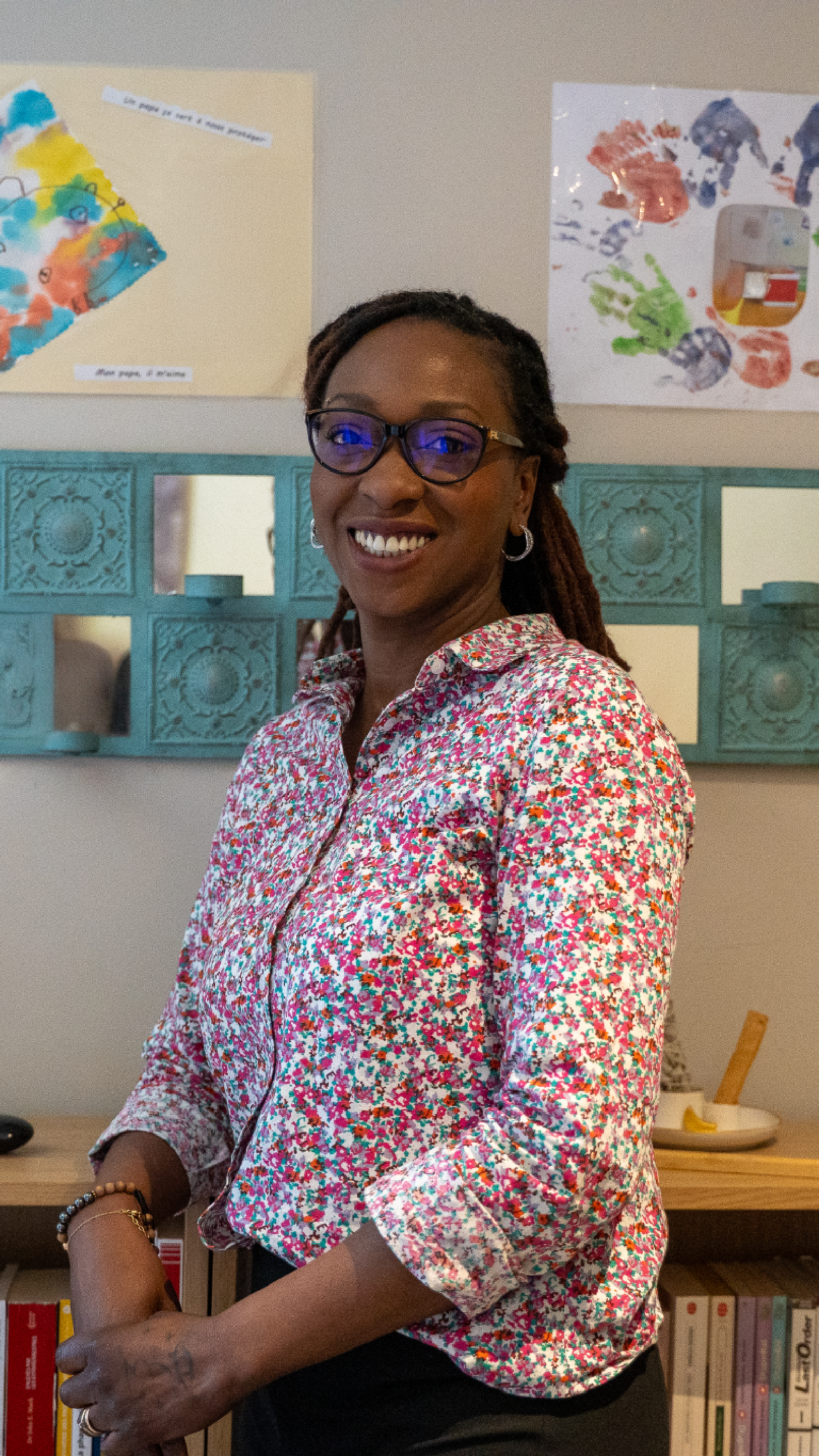 Portrait de la fondatrice de LuminaPro, souriante, debout devant une étagère, dans un cadre accueillant et chaleureux.