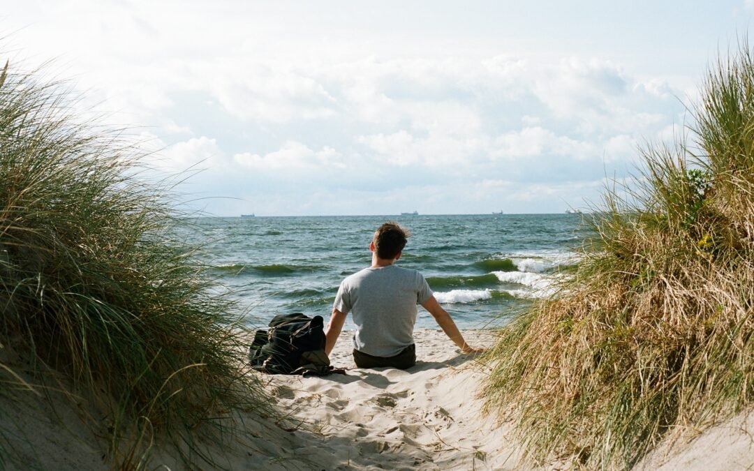 Personne assise face à la mer, symbolisant l’introspection et l’exploration du subconscient en hypnose